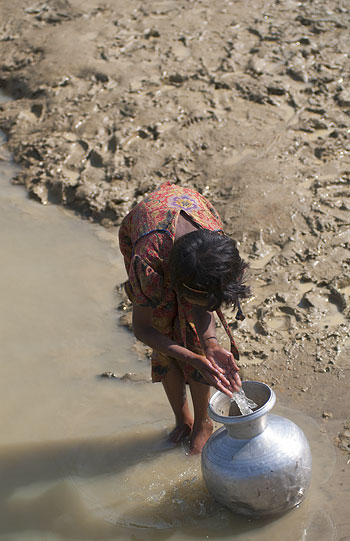 難民キャンプ横のため池で僅かに残った水を汲むロヒンジャ難民の女の子