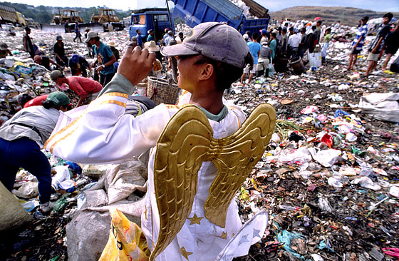ゴミの中から「天使の羽」が付いた衣装を引っ張り出して身に付け、ふざけまわる男の子（フィリピン）